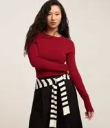 Suéter ajustado de punto color crema, con cuello redondo y mangas largas con botones metálicos en los puños. Confeccionado con viscosa sostenible.