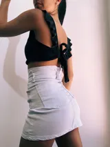 Crop top negro con textura brillante, breteles anchos con volados y espalda descubierta que se ata con lazos.