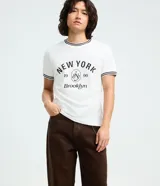 Pantalón de sarga color marrón oscuro, con corte super baggy, cintura con trabillas, bolsillos laterales y traseros, y cierre frontal con botón y cremallera. Incluye una cadena metálica decorativa en la cintura.