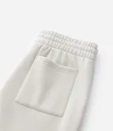 Pantalón jogger de algodón con felpa, color beige, con cintura elástica, cordón ajustable, bolsillos laterales y puños elásticos en los tobillos.