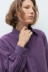 Camisa de manga larga con estampado de cuadros pequeños en tonos violeta y rojo, con cuello clásico y cierre frontal de botones.