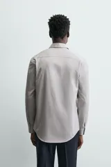 Camisa de manga larga para hombre, color gris claro con micro-estampado de cuadros sutiles. Presenta cuello italiano y cierre frontal de botonadura.