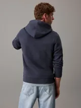 Buzo de felpa azul marino con capucha y cordones ajustables. Logotipo de Calvin Klein Jeans estampado en el pecho.