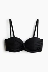 Top de bikini balconette negro con copas acolchadas, aros, varillas laterales y detalle girado en el centro. Incluye tirantes ajustables y extraíbles.