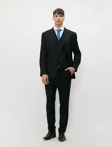 Traje de tres piezas color negro, compuesto por saco de dos botones, chaleco entallado y pantalón de corte slim, confeccionado en tejido de fantasía con spandex.