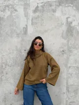 Polera de tejido de punto acanalado en color ocre, con cuello alto y diseño de mangas amplias. Presenta un corte recto y holgado con un detalle de cuello abierto lateral.