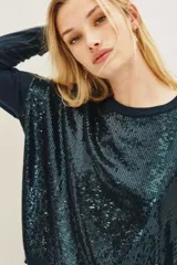 Sweater de punto en color azul oscuro, con cuello redondo y mangas largas. Presenta un diseño frontal completamente cubierto de lentejuelas brillantes en tonos azulados y verdosos.