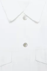 Sobrecamisa de denim blanca con cuello solapa, manga larga, bolsillos de plastrón con solapa, bajo deshilachado y cierre frontal con botones metálicos.