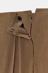 Pantalón de tiro alto color marrón, con nervio frontal marcado y bajo acabado en estilo fuseau (con tira elástica para pasar por debajo del pie).