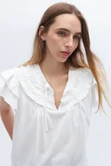 Blusa blanca de lyocell y algodón, con escote fruncido con volados y lazos.