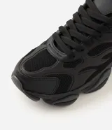 Championes estilo dad sneaker de poliuretano color negro, con recortes en relieve de inspiración tribal y paneles texturizados. Cuentan con suela gruesa voluminosa y cierre de cordones.