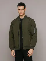 Campera bomber Calvin Klein color verde militar con diseño acolchado en forma de rombos. Tiene cierre frontal con cremallera, cuello, puños y dobladillo acanalados, bolsillos laterales y un bolsillo con cremallera en la manga izquierda con el logo de la marca.