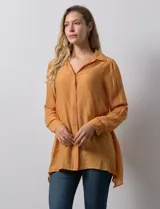 Camisa larga de rayón, con cuello clásico, cierre frontal con botones y mangas regulables con presilla. Presenta un diseño holgado con tajos laterales en el ruedo.