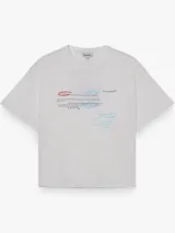 Remera de corte boxy y fit relajado, color blanco, con cuello redondo y mangas cortas. Presenta un diseño estampado en el frente con tipografía estilo manuscrito y detalles en colores rojo y celeste.