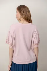 Remera de algodón color blanco, con cuello redondo y mangas cortas holgadas que presentan detalles de encaje broderie.