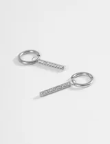 Aros de acero quirúrgico con diseño de argolla pequeña y dije colgante en forma de barra vertical decorado con strass.