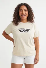 Remera color lila con estampa tipográfica marrón en el frente y mangas cortas.