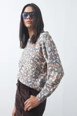 Sweater de punto con diseño de estampado animal print abstracto en tonos tierra y azul claro. Presenta cuello redondo a la base, mangas largas levemente amplias y terminaciones acanaladas en puños y ruedo.