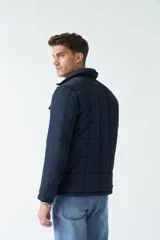 Campera negra de nylon capitoneada, con cuello medio y bolsillos tipo sobre con botón.