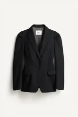 Blazer negro de corte recto de la colección Zara Studio, con solapas de muesca, cierre frontal de dos botones y bolsillos con solapa. Presenta mangas largas con pliegues estructurados en los hombros y forro interior a rayas a contraste.