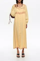 Vestido midi de línea A color amarillo, confeccionado en mezcla de lyocell y viscosa, con botones frontales, escote cuadrado y tirantes finos. Presenta detalles de encaje en contraste y mini tablas verticales en el frente.