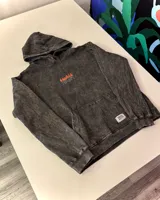 Canguro gris con efecto lavado, de corte holgado y con capucha. Presenta un estampado pequeño en el pecho y un bolsillo tipo canguro.