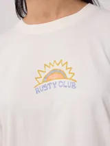 Remera color salmón de corte holgado, con estampado pequeño en el frente que incluye un arcoíris y el texto "Rusty Club".