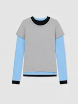 Remera de manga larga con diseño de capas superpuestas, que combina una remera gris de manga corta sobre una remera celeste de manga larga, con detalles de cuello y puños en color negro.