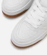 Championes blancos de caña baja con recortes, lazo por cordón y suela contrastante color marrón.