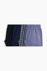 Pack de cuatro calzoncillos tipo boxer de tela de algodón suave, con cintura elástica y cierre de botones. El set incluye un modelo liso azul marino, uno con microestampado, uno a cuadros y uno a rayas verticales.
