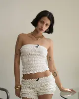 Top strapless blanco con detalle de frunces y moño negro en el centro.