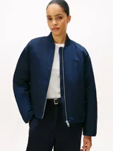 Campera bomber de satén azul marino con acabado repelente al agua y diseño acolchado. Presenta cuello estilo béisbol de punto canalé, cierre frontal de cremallera y logo de Tommy Hilfiger bordado en fuente script en el pecho.