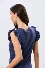 Remera de algodón azul melange con escote redondo y mangas cortas adornadas con doble volado de broderie en los hombros.