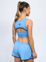 Top deportivo de Umbro para mujer, color azul marino, con el escudo del Club Nacional de Football en el centro y banda elástica inferior con la marca estampada.