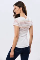 Remera de manga corta con cuello redondo, de color beige con diseño de franjas horizontales en tonos celestes y rosados en la parte superior.