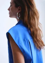 Camisa de popelín color azul, de diseño oversize y sin mangas, con cuello camisero, bolsillo parche delantero y cierre frontal con botones.