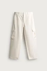 Pantalón cargo relaxed fit de color blanco, confeccionado en tejido de algodón. Presenta bolsillos de plastrón con solapa en las perneras y cierre frontal con cremallera y botón.