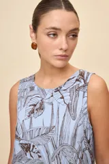 Vestido corto sin mangas de color celeste con estampado botánico en tonos marrones, de silueta amplia, escote redondo y volado en el ruedo.