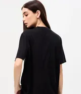 Remera de algodón negro con cuello redondo y mangas cortas, con estampa frontal inspirada en la banda Kiss y detalles de strass.