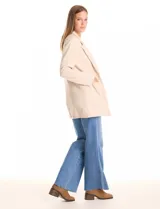 Blazer de tejido soft color beige, con silueta relajada y corte largo. Presenta cuello con solapas muesca, frente abierto sin botones y dos bolsillos de parche frontales.