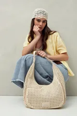 Cartera de hombro color beige con diseño calado y estructura semirrígida.