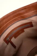 Bolso tipo tote color marrón de cuero suave, con doble asa larga decorada con nudos en los extremos inferiores y detalle de logo grabado en el frente.