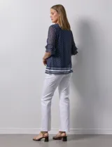 Blusa Harper de microtul estampado azul con lunares blancos, cuello redondo, escote en U con aplique de aros y mangas cortas amplias.