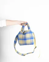 Bolso tipo tote bag con estampado a cuadros en tonos azul, beige y gris. Tiene doble asa corta y correa larga ajustable.