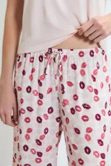 Pijama compuesto por una remera de manga corta en color rosa claro con un pequeño bordado de labios en el pecho y un pantalón largo estampado con motivos de labios en tonos rojos y rosas.