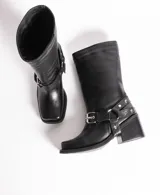 Bota de cuero negra con caña media, punta cuadrada, taco bloque y arnés con hebillas y tachas plateadas.