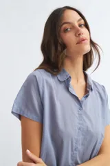 Camisa celeste de manga corta con cuello camisero y abotonadura frontal.