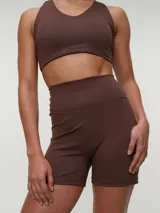 Top deportivo negro con espalda nadadora, copas removibles y detalle de logo sutil en el elástico inferior.