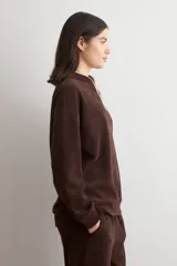 Sweater de tejido acanalado color marrón, con cuello alto y cierre frontal parcial. Presenta un diseño holgado de manga larga con hombros caídos.