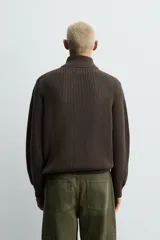Jersey de punto perlado con cuello perkins y cierre frontal de cremallera. Presenta un corte regular fit, manga larga y acabados en rib en puños y bajo.